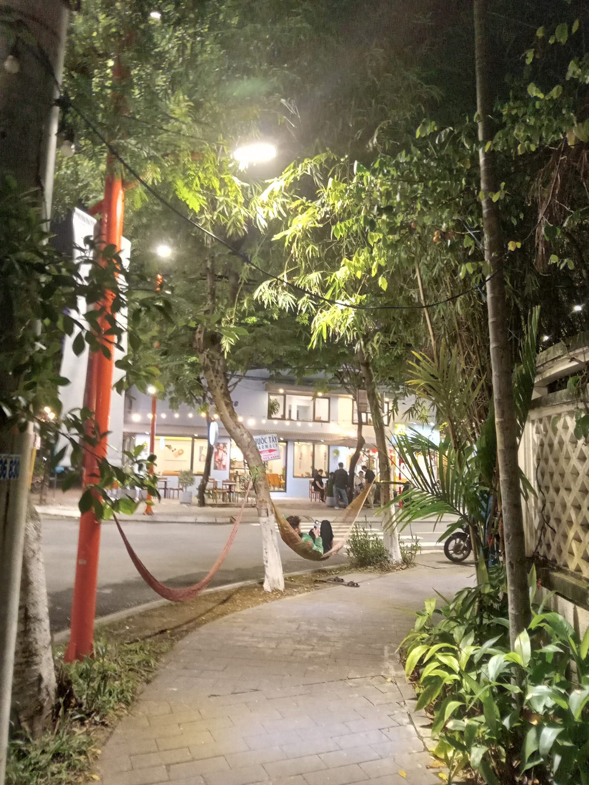 A man relaxes in a hammock strung near the sidewalk in Vietnam