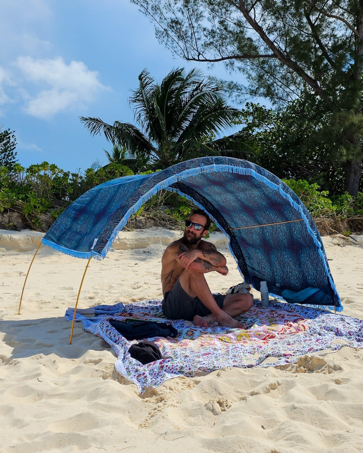 Suniela portable beach cabana with Ocean Waves cotton canopy adjusted to one side for sun protection on a sandy beach
