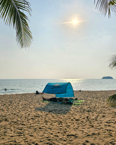 Turquoise Suniela portable beach cabana set up on a sandy beach by the ocean