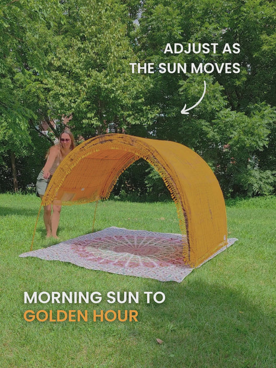 Video of a woman sliding the adjustable canopy of a Tiger’s Eye Suniela portable beach cabana from side to side on park grass, so the shade follows the sun.