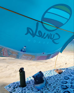 Turquoise cotton shade tent with large mesh pockets for beach essentials