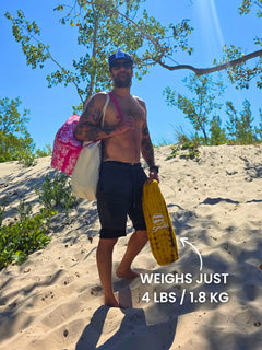Man walking up a sand dune carrying beach bags and a Tiger’s Eye Suniela cabana in its 4 lb carry bag